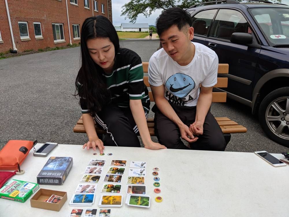 Two students playing a card game outdoors